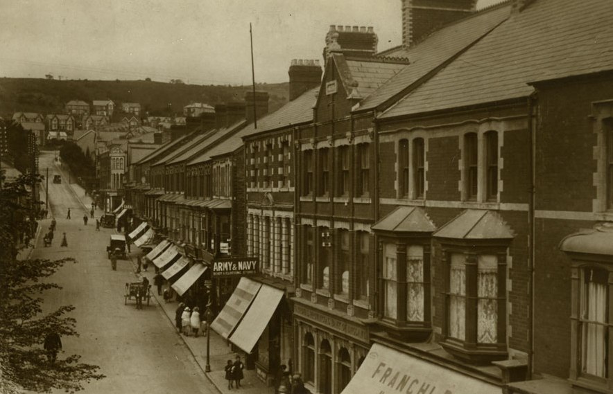 Maesteg high street in the early 1900s, with shopfronts and striped awnings along the road